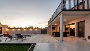 A modern outdoor patio with a stone pool, lounge chairs, and a covered seating area. - Villa Flora Zadar Villas (Benkovac)