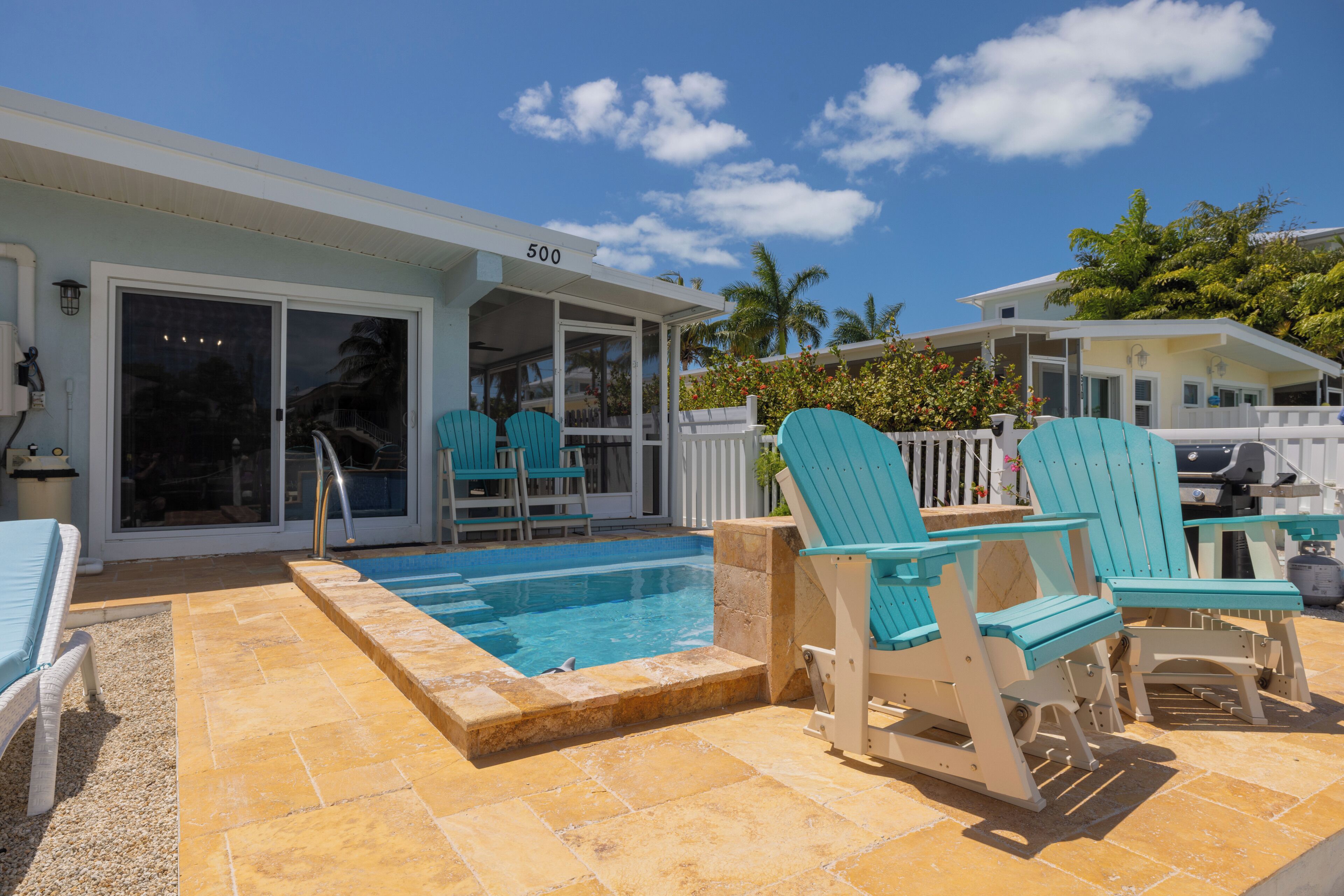 A pool area with a covered deck, outdoor seating, and a building with a number 500 sign.