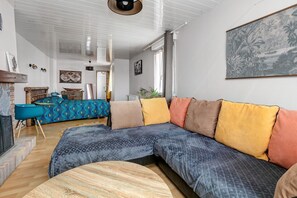 A modern living room with a sectional sofa, a round coffee table, and a fireplace. - La casa d’Antoine – Fisherman’s House on the Loire (Paimbœuf)