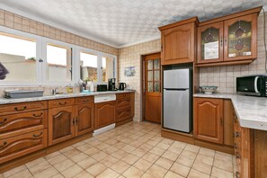 A kitchen with wooden cabinets, a stainless steel refrigerator, a microwave, and a dishwasher.