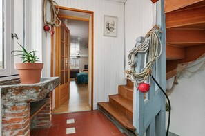 A staircase with a rope decoration, a potted plant, and a wooden door leading to another room.