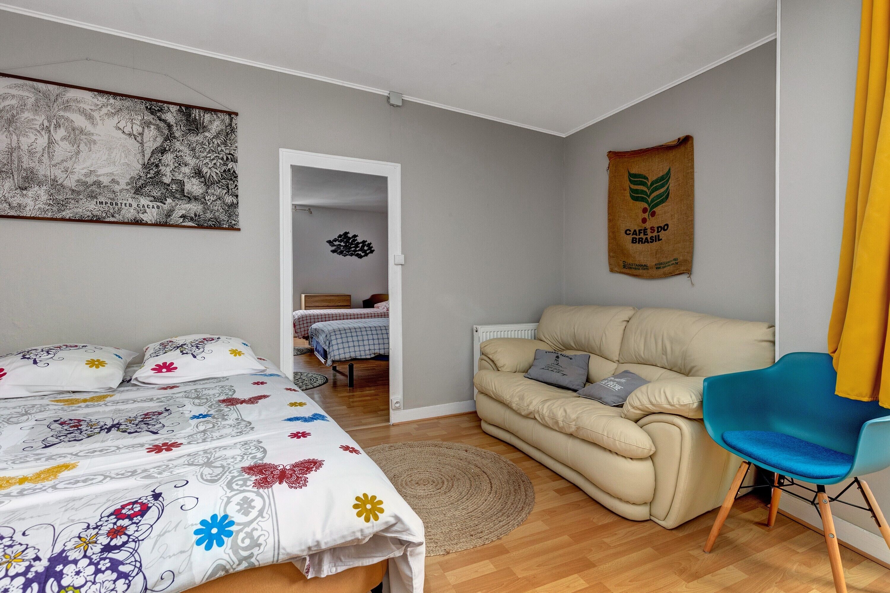 A bedroom with a bed, a sofa, a chair, a painting, and a wall hanging.