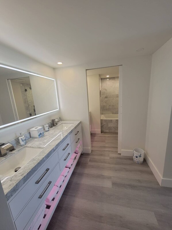 A modern bathroom with a large mirror, a vanity with drawers, and a shower area. - Gulf-Front Seachase Escape w/ Beach Service (Panama City Beach)