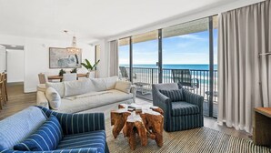 Ein geräumiger Wohnbereich mit Balkon und Meerblick, ein Essbereich sowie ein moderner Kronleuchter.