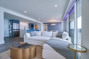 Ein modernes Wohnzimmer mit einer Couch, einem Couchtisch und Blick ins Freie.