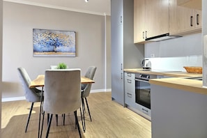 Une cuisine moderne avec des meubles gris, un plan de travail en bois et un coin repas comprenant une table et des chaises.