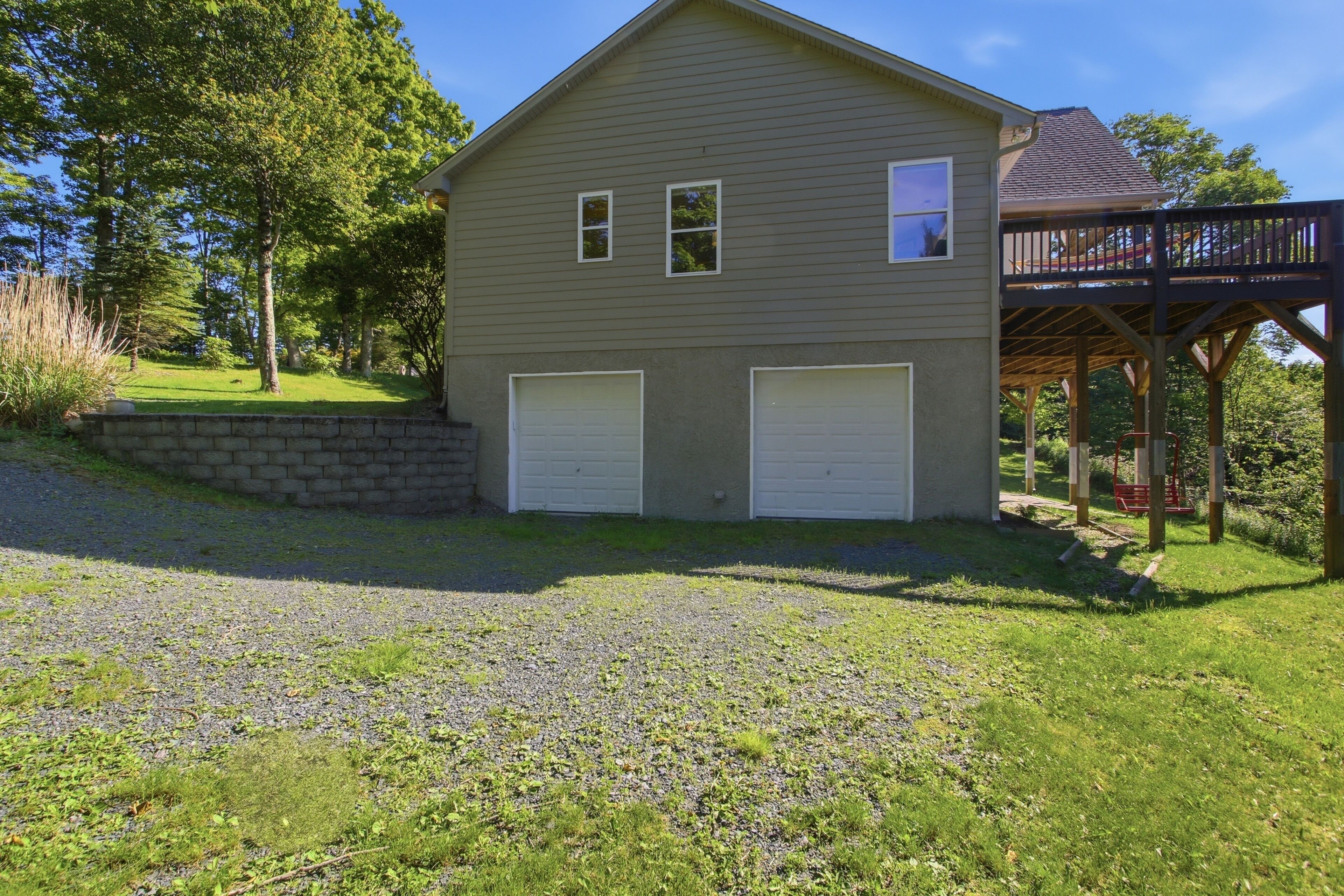 A two-story house with a garage, a deck, and a grassy yard.