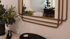 A room with a large mirror, a potted plant, and a black bowl with lemons. - Kove Apartment - G01 (Kiama)