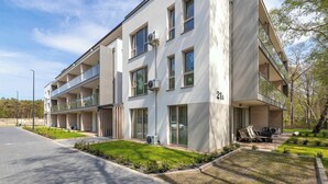 Un edificio moderno de varios pisos con balcones, un camino de entrada pavimentado y un césped bien cuidado.