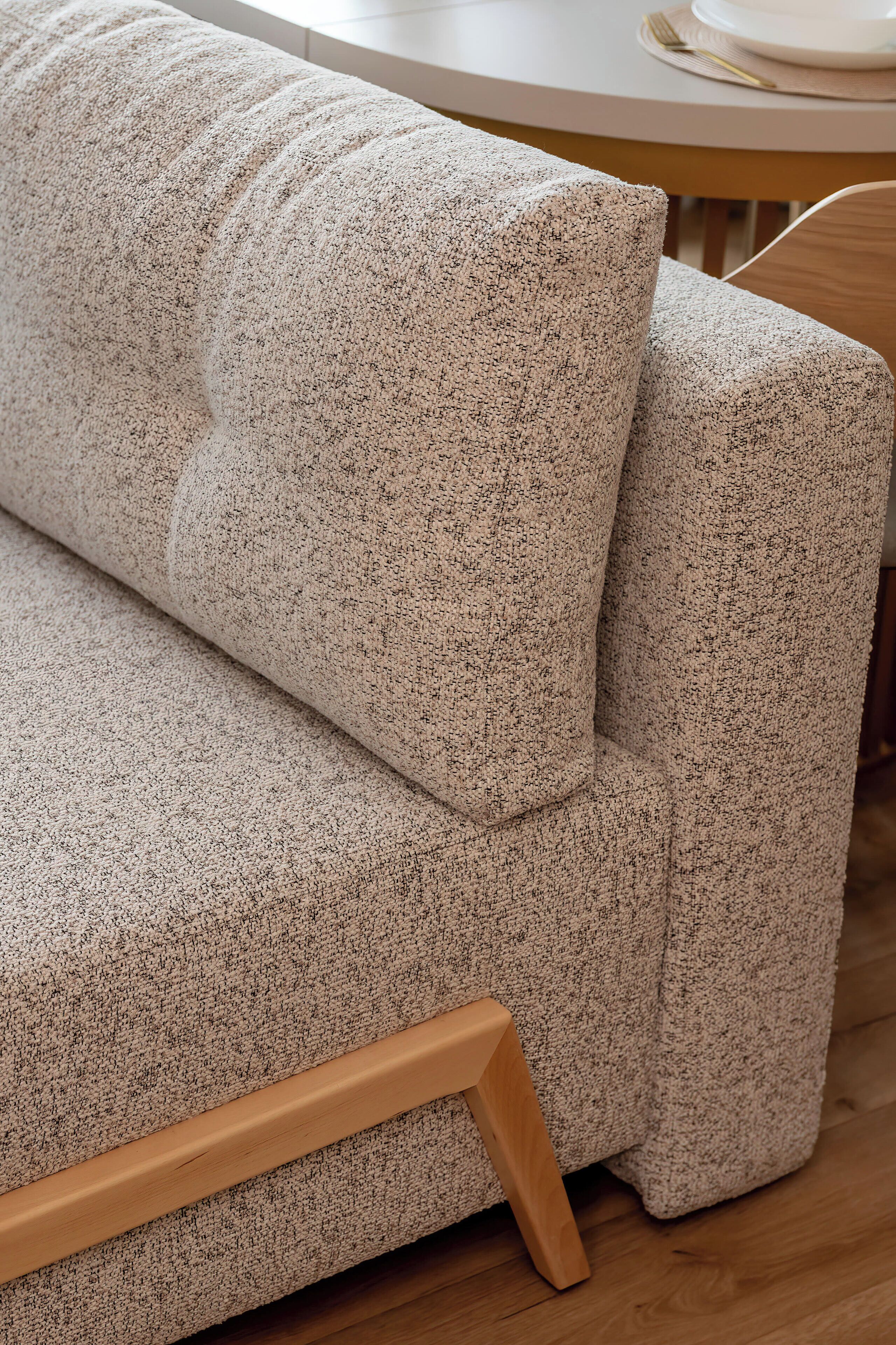A sofa with a textured fabric and wooden legs.