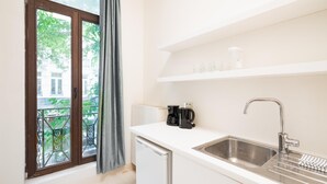 Een compacte keuken met een ingebouwde vaatwasser, een roestvrijstalen spoelbak en een koffiezetapparaat.