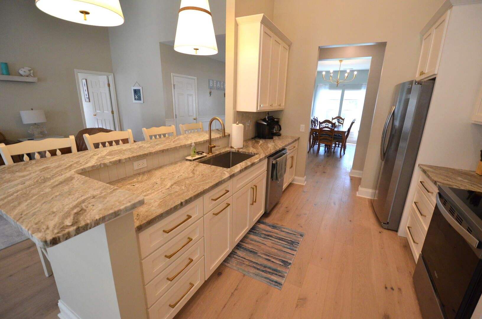 A kitchen with a granite countertop, stainless steel appliances, and a dining area with wooden chairs.