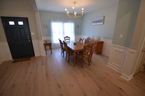 Un comedor con mesa y sillas de madera, una lámpara de araña y una puerta.