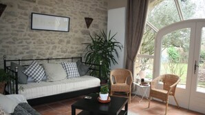 Un salon avec un mur en pierre, un canapé, une table basse, des fauteuils en osier et une plante en pot.