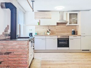 A kitchen with a brick stove, white cabinets, a wooden countertop, and a built-in oven. - Lovely apartment for 4 people with pets allowed (Ebensee)