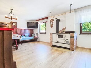 A room with a wooden floor, a bed with a red headboard, a TV mounted on the wall, a wooden cabinet, and a window with a view of greenery. - Lovely apartment for 4 people with pets allowed (Ebensee)