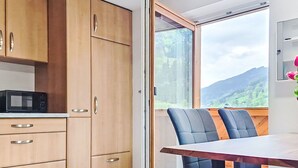 Et moderne køkken med træskabe, en mikrobølgeovn og et spiseområde med bord og stole.