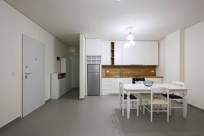 A modern kitchen with white cabinetry, a wooden countertop, and a dining table with chairs. - Sanpietro Vacation Apartment 056 (Ishëm)