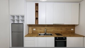 A kitchen with white cabinets, a wooden countertop, a stainless steel sink, a built-in oven, and a refrigerator. - Sanpietro Vacation Apartment 056 (Ishëm)