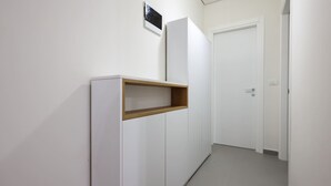 A hallway with a white wardrobe, a wooden shelf, and a closed door. - Sanpietro Vacation Apartment 056 (Ishëm)