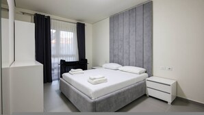 A modern bedroom with a bed, bedside tables, a wardrobe, and a window with curtains. - Sanpietro Vacation Apartment 056 (Ishëm)