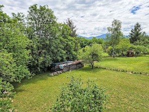 A grassy park with trees, a small wooden structure, and a stone wall.