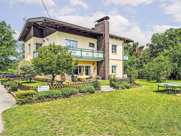 Ein zweistöckiges Gebäude mit Balkon, Backsteinschornstein und gepflegtem Rasen.