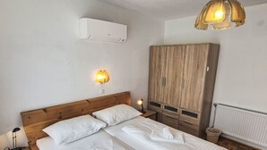 Camera da letto con un letto in legno, due comodini, un armadio, un condizionatore d'aria e un punto luce a parete.