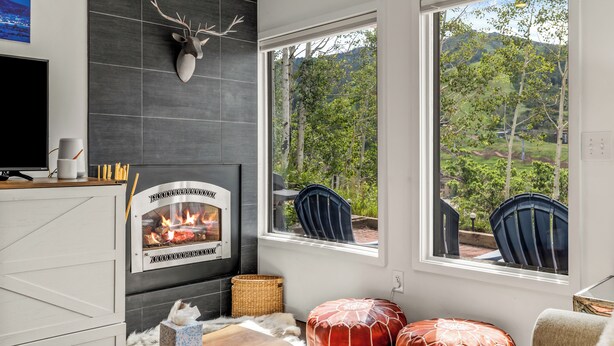 Ein modernes Wohnzimmer mit Kamin, großen Fenstern und Blick ins Grüne.