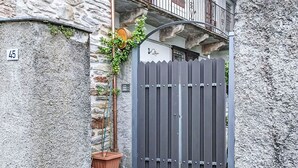 Ein verschlossenes Tor mit einer Steinmauer, einem Blumentopf und einem Metallgitter.