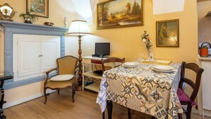 Ein Essbereich mit Tisch für zwei Personen, Kamin, Fernseher und einem Gemälde an der Wand.