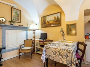 Ein Essbereich mit Tisch für zwei Personen, Kamin, Fernseher und einem Gemälde an der Wand.
