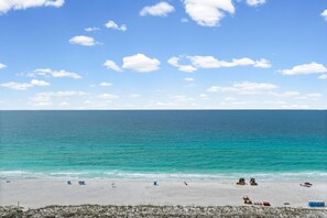 Ein Strand mit blauem Himmel, ruhiger See und Strandzubehör.