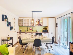 Eine moderne Küche mit weißen Schränken, einer gestreiften Tischdecke und hängenden Pendelleuchten.