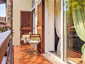 Eine kleine Terrasse mit Tisch und Stühlen, eine Holztür sowie eine Glastür.