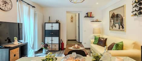 Una sala de estar bien iluminada con un sofá, una mesa de comedor con un pastel y un televisor.