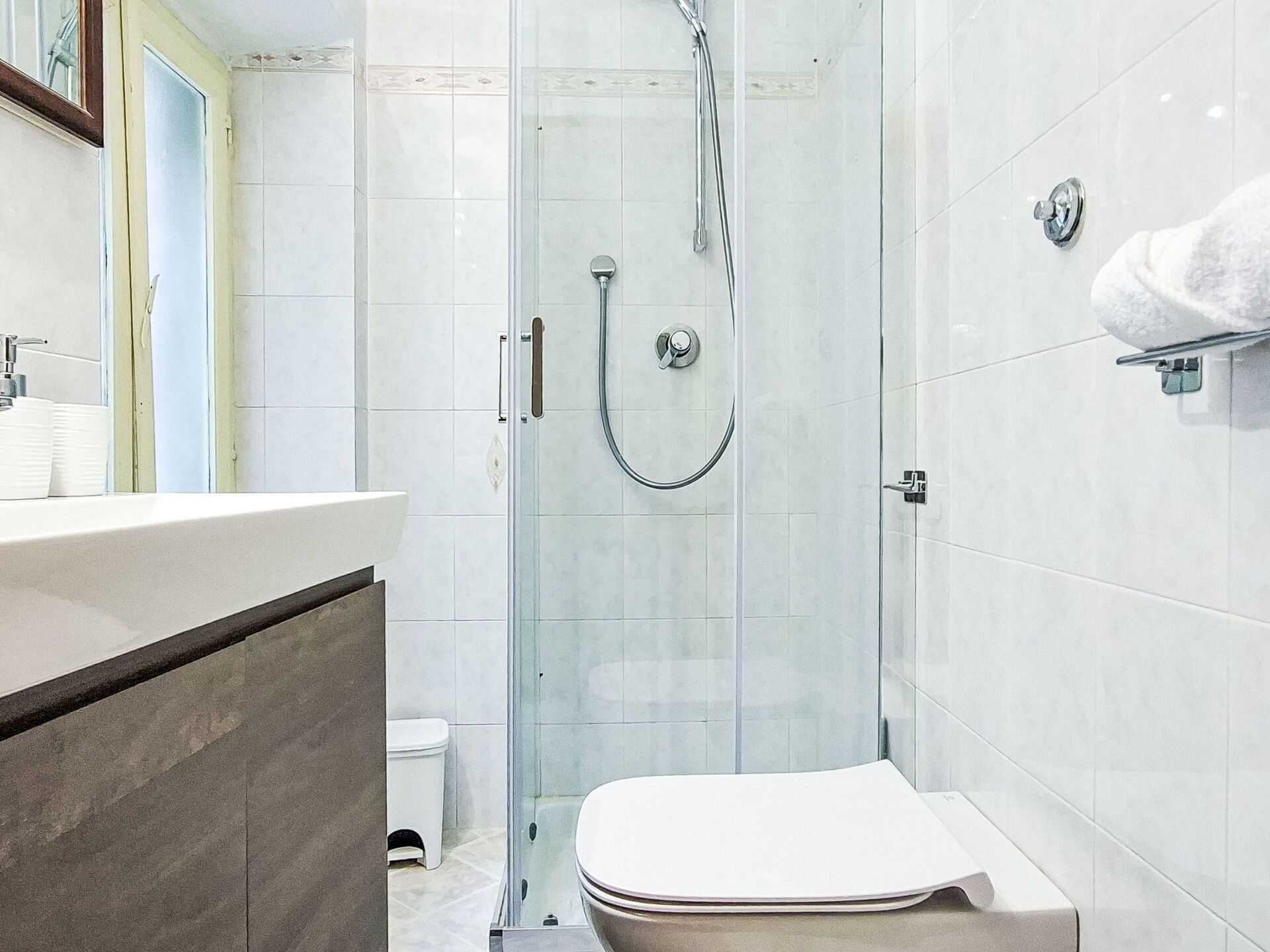 Une salle de bain moderne avec une douche à parois de verre, des toilettes et un lavabo avec un miroir.