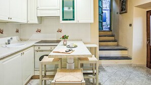 Une cuisine de taille réduite avec des meubles blancs, une table à manger et une petite fenêtre.
