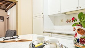 Un coin repas avec une table dressée pour deux personnes, un vase orné de motifs floraux et un livre posé sur la table.