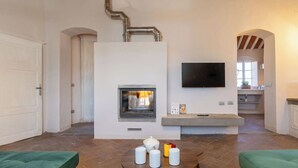 Ein Wohnzimmer mit Kamin, Flachbildfernseher und grünen Polstersofas.