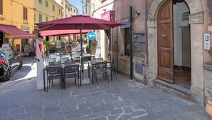 Ein Straßencafé mit Tischen, Stühlen und einem Hauseingang.
