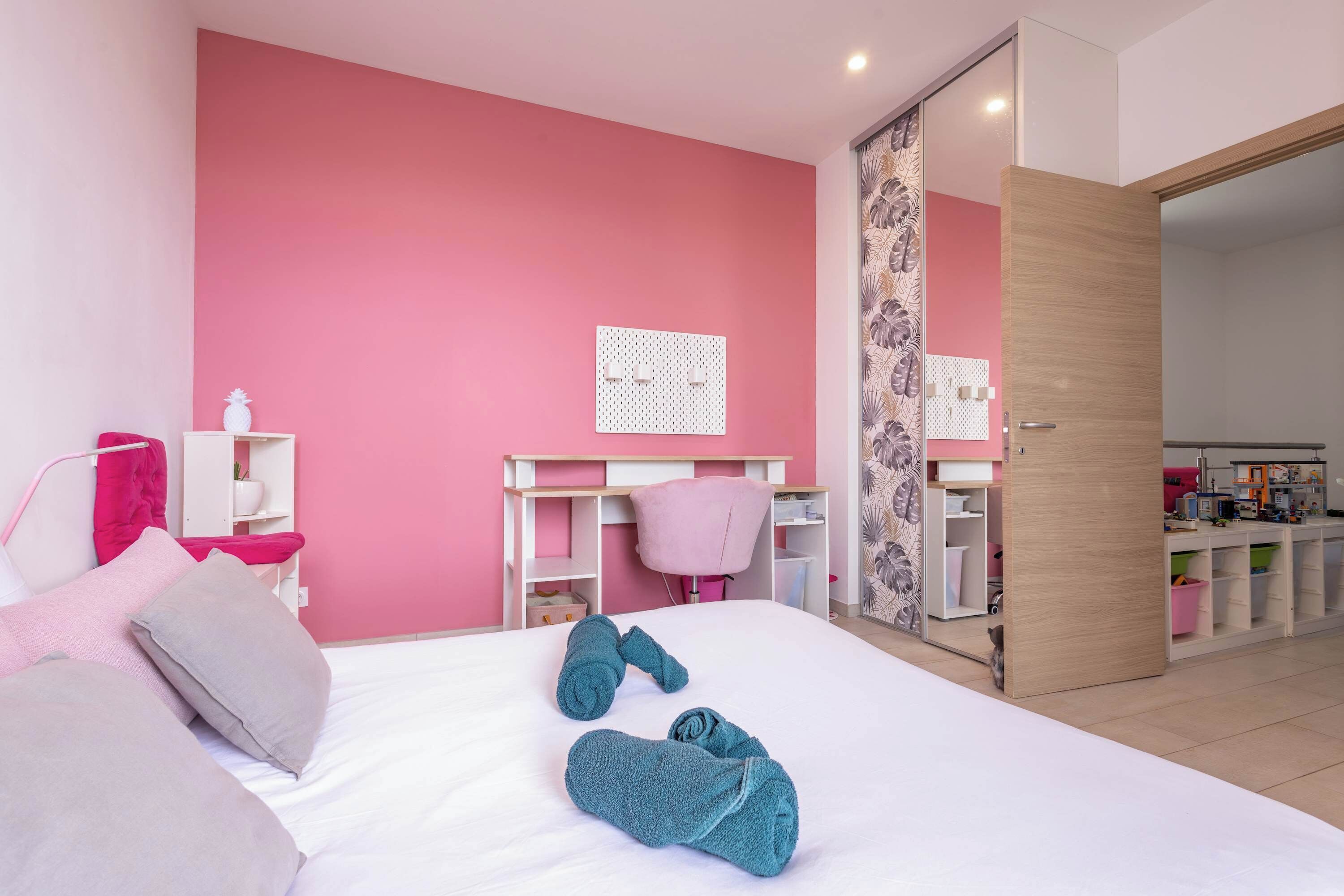 Une chambre à coucher avec un lit, des oreillers, un bureau, une chaise et une armoire.