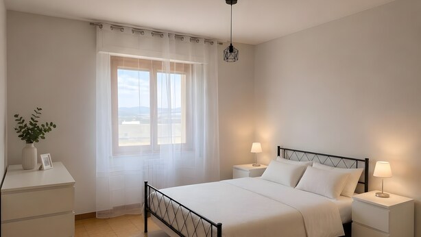 Ein Schlafzimmer mit Bett, Nachttischen, einem Fenster mit durchsichtigen Vorhängen, einer Pflanze und Blick ins Freie.