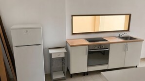 Eine kleine Küche mit Kühlschrank, Herd, Spüle und einer Arbeitsplatte.