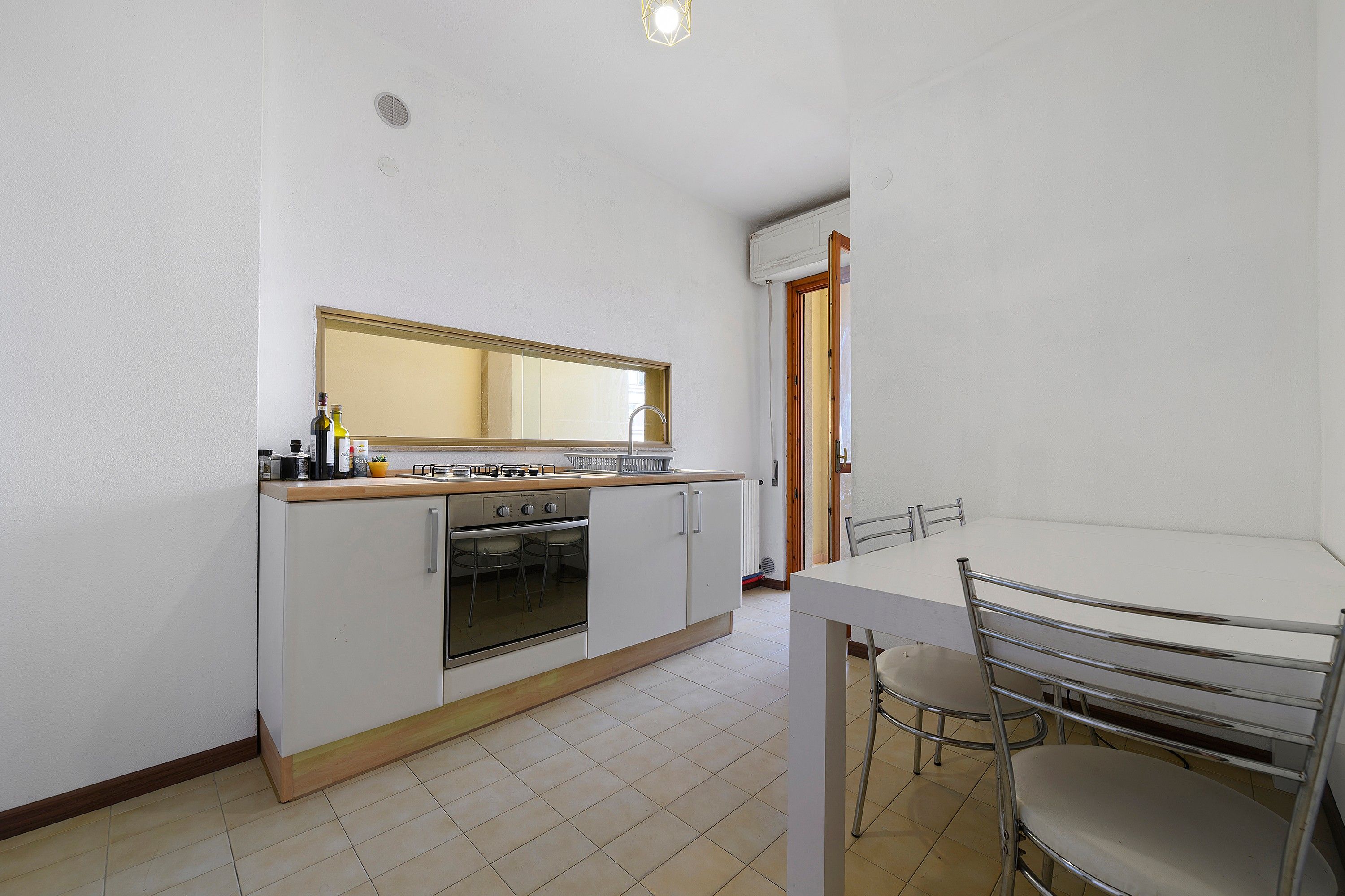 Una cocina funcional con estufa, horno y una mesa de comedor con sillas.