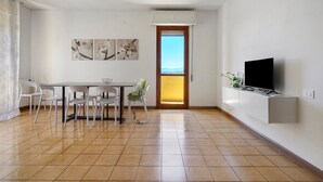 Ein modernes Wohnzimmer mit Essbereich, Fernseher und Kunstwerken an der Wand.