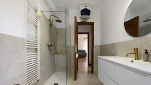 Ein modernes Badezimmer mit begehbarer Dusche, einer Badewanne und einem großzügigen Waschtisch mit Spiegel.