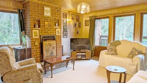 A cozy room with a fireplace, a sofa, a table, and a television. - Ancton Way by the Sea - sleeps 9 guests  in 4 bedrooms (Bognor Regis)