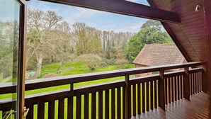 A wooden balcony with a view of a green landscape and trees. - Ancton Way by the Sea - sleeps 9 guests  in 4 bedrooms (Bognor Regis)