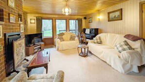 A cozy living room with a wooden ceiling, a television, a piano, and a fireplace. - Ancton Way by the Sea - sleeps 9 guests  in 4 bedrooms (Bognor Regis)